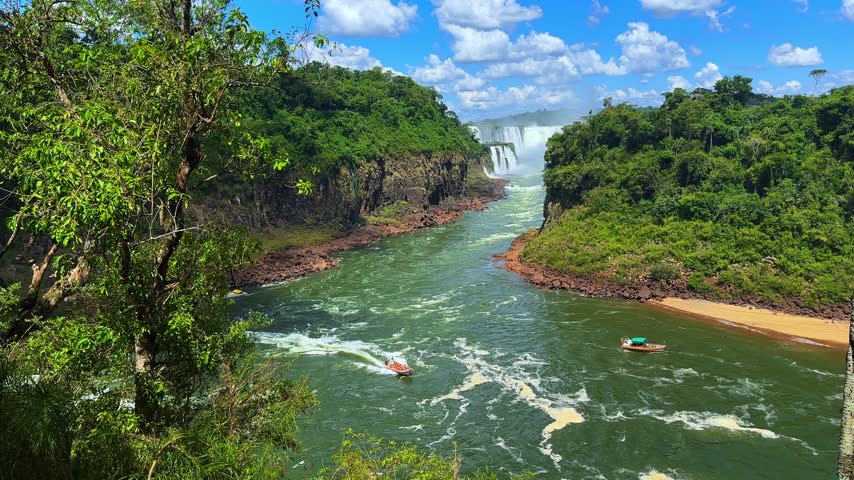 Scenic view of Iguazu Falls in Argentina with lush green jungle and tourist boats on the river
