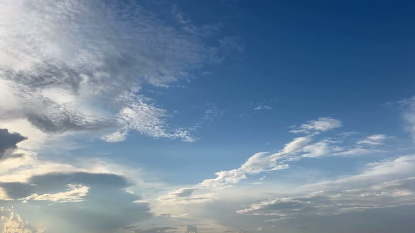 Dramatic cloudy sky changing color from blue to orange as the sun sets with beautiful sun rays