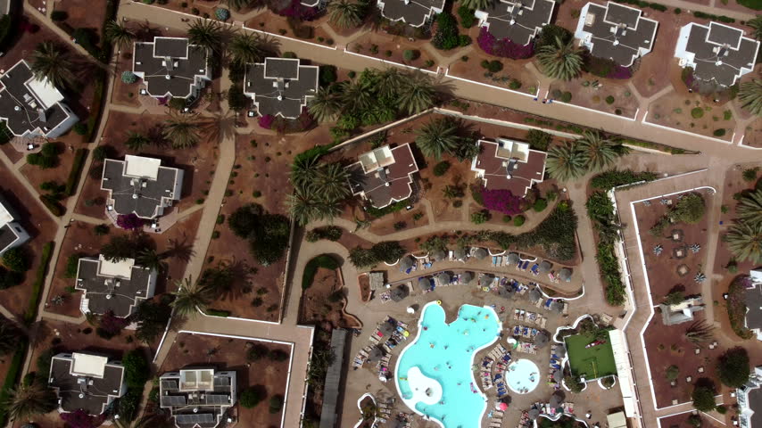 An aerial view of a resort with multiple buildings pools and landscaping