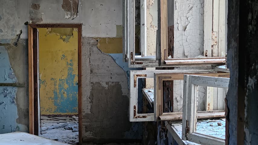 An old door with peeling paint and rusty hinges, set in a rundown building.