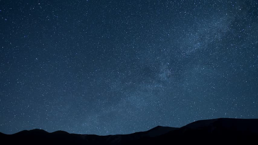 Night starry sky with Milky Way galaxy over the hill silhouette. Space cosmos Timelapse.