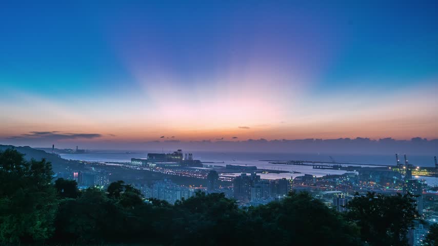 High angle panoramic view of urban city lights, coastal roads, and the ocean at twilight in Bali district, New Taipei, Taiwan.