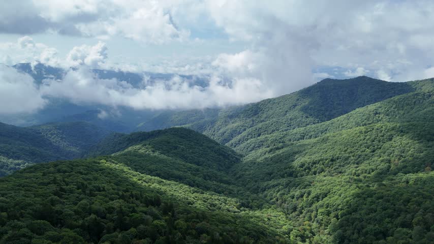 Scenic aerial view of clouds over green mountains