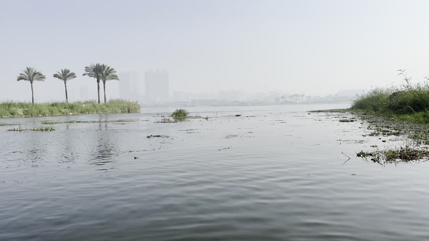 View from a traditional felucca sailing boat on the River Nile in Cairo, Egypt, sail, rippling water and riverbank passing by