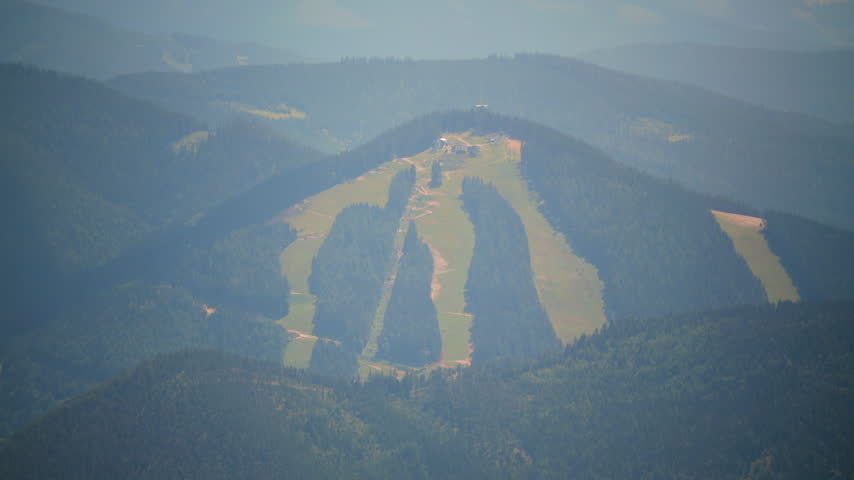 This shows an aerial view of a landscape with fields and mountains. Changes are subtle.