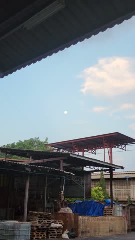 Evening blue sky and soft clouds over industrial building roof structure.