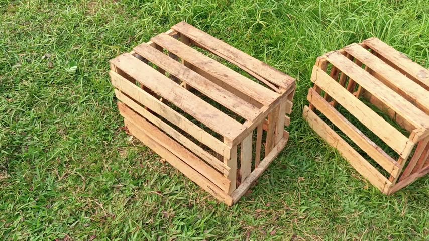 Two empty wooden crates sitting on green grass field camera panning shot