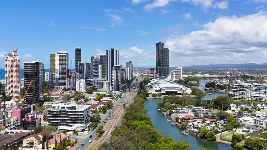 High angle aerial shot of Gold Coast skyscrapers, roadways, and waterways under bright sunny skies.
