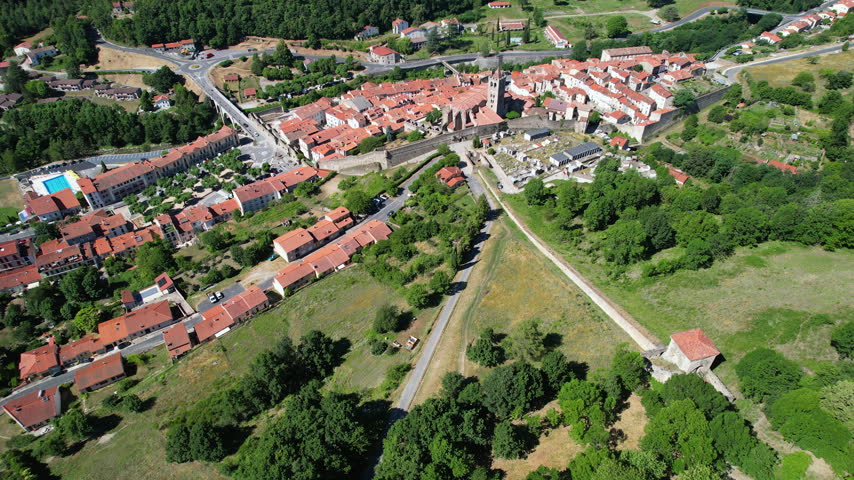 Forward reveal aerial shot of the medieval walled town of Prats-de-Mollo-la-Preste, featuring the iconic Romanesque Church of Sainte-Juste-et-Sainte-Ruffine with its stone bell tower and red tiled roofs, France.