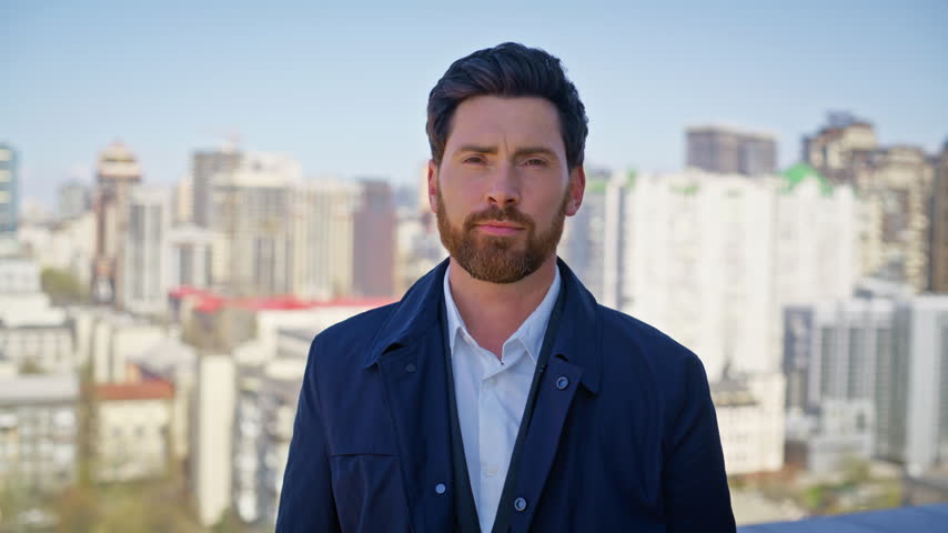 Serious business man standing rooftop arms crossed. Confident male entrepreneur portrait, bearded professional looking camera, sunny city skyline background, corporate leadership success concept.