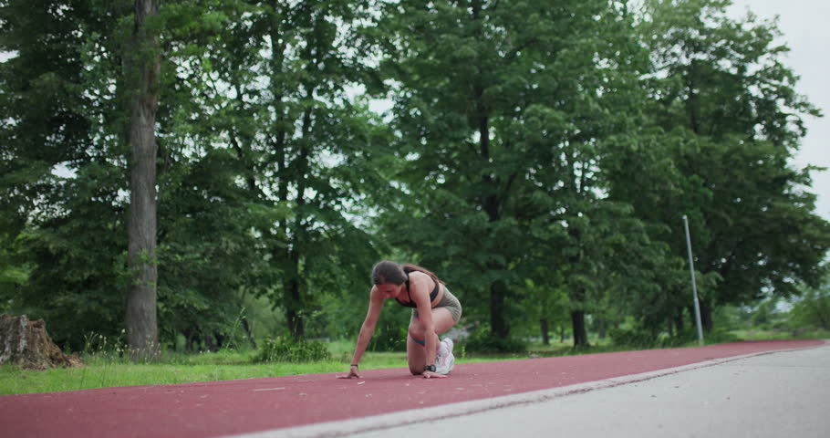 A focused female athlete prepares to sprint, showcasing dedication and readiness for a powerful run.