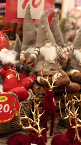 
Vertical screen Christmas gnomes and decorative reindeer displayed in a festive store sale section surrounded by colorful seasonal decorations and holiday gifts