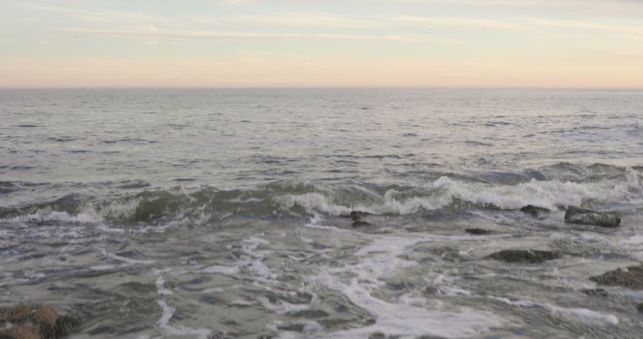 Gentle Waves Washing Over Coastal Rocks and Tide Pools at Sunset