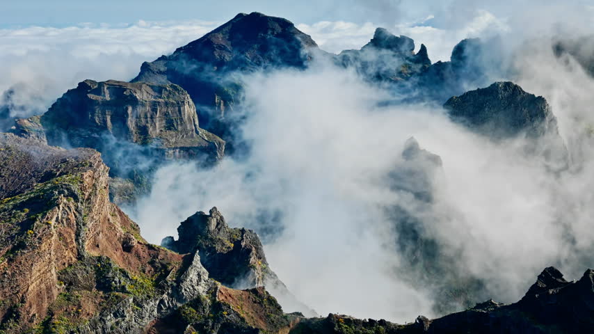 Rock pinnacle amid low clouds near Pico do Arieiro, Madeira, Portugal. Sheer mountain walls and narrow ridge above mist-filled ravines