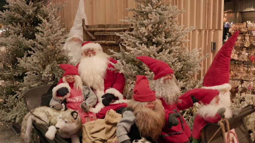 Santa gnomes in a sleigh surrounded by illuminated Christmas trees and festive garlands creating a colorful holiday installation inside a shopping mall