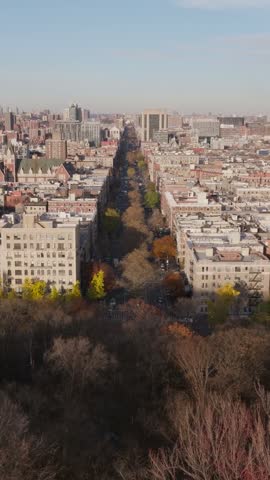 Vertical video: High angle view of a train pulling into a station in Hoboken, New Jersey, with commuters waiting on the platforms along a river showing urban transportation system