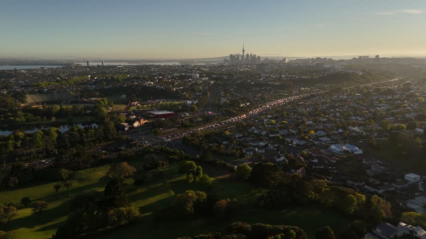 Aerial view of Auckland city skyline with Sky Tower and highway traffic at sunset in New Zealand.