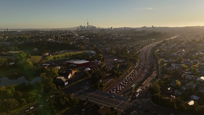 Aerial view of Auckland skyline with Sky Tower and highway traffic on motorway at sunset in New Zealand.
