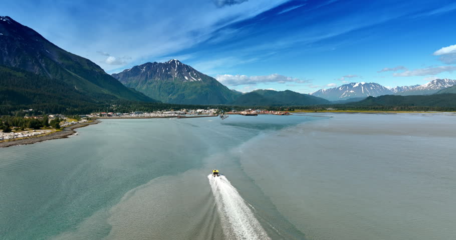 Motorboat heading to the cityscape located in Alaska, USA. Picturesque mountains at backdrop.