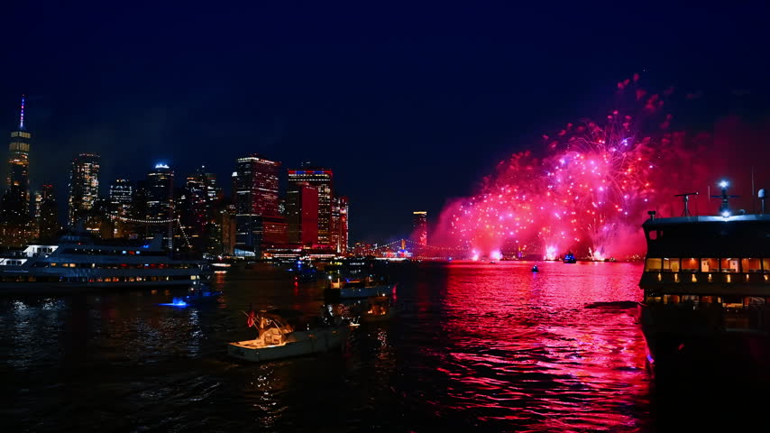 Flashes of fireworks coloring the dark sky in pink. Firework show over the East River in New York on the 4th of July.