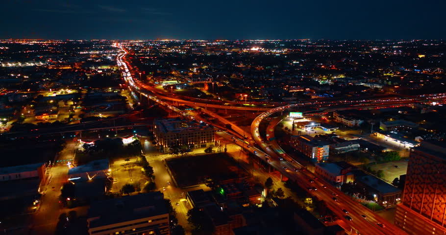 Approaching the lively interchange in the cityscape of Houston, Texas, USA. Hectic traffic on the highways and streets of the city at night.