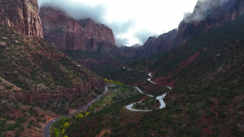 aerial View of Zion National Park Canyon with Dramatic Clouds Over Red Rock Cliffs and Winding Road