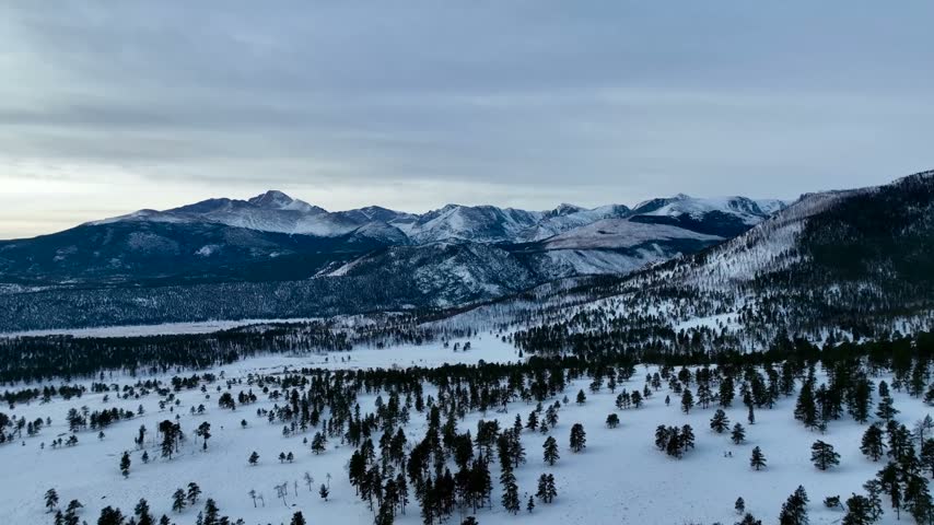 aerial Cinematic Drone View of Snow-Covered Valley and Rocky Mountains at Winter Dusk in Colorado