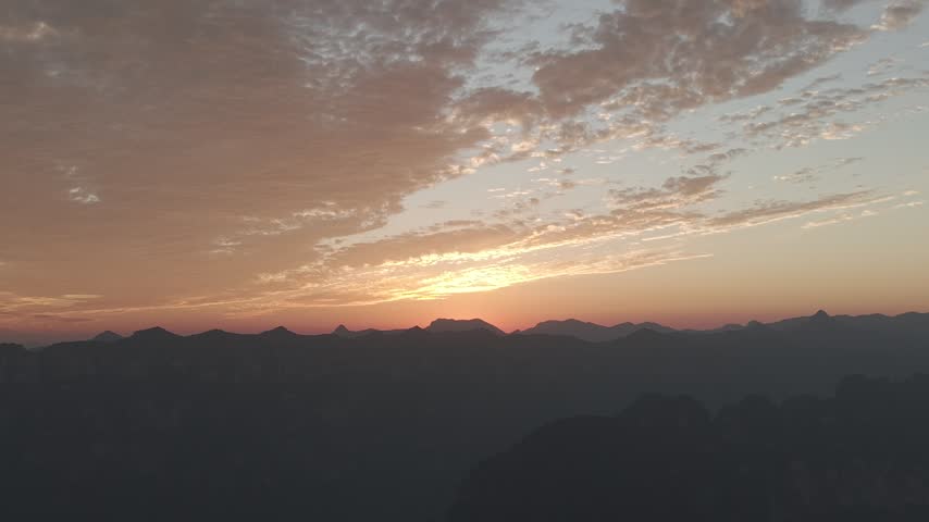 Aerial view of a vibrant autumn sunset over Taihang Mountains, China. Pink and orange textured clouds fill the sky above dark silhouettes of Wanxian peaks.