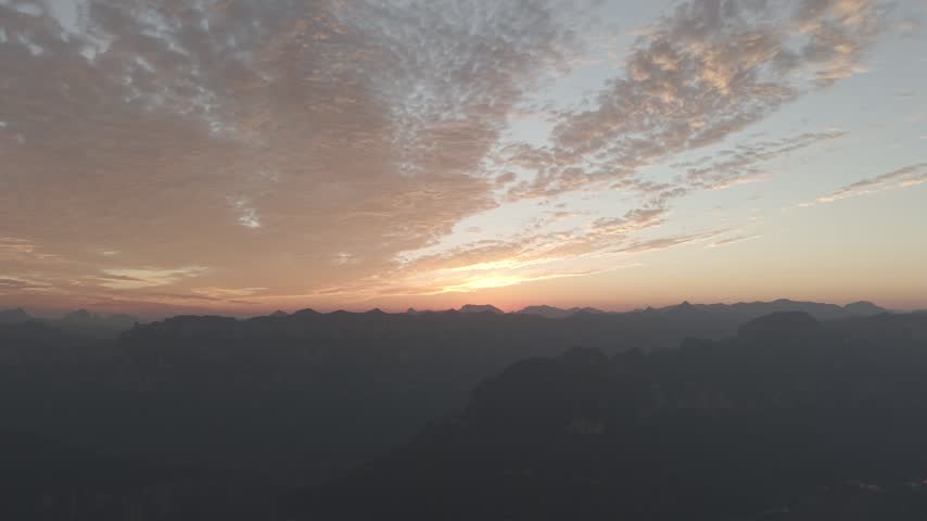 Aerial view of a vibrant autumn sunset over Taihang Mountains, China. Pink and orange textured clouds fill the sky above dark silhouettes of Wanxian peaks.