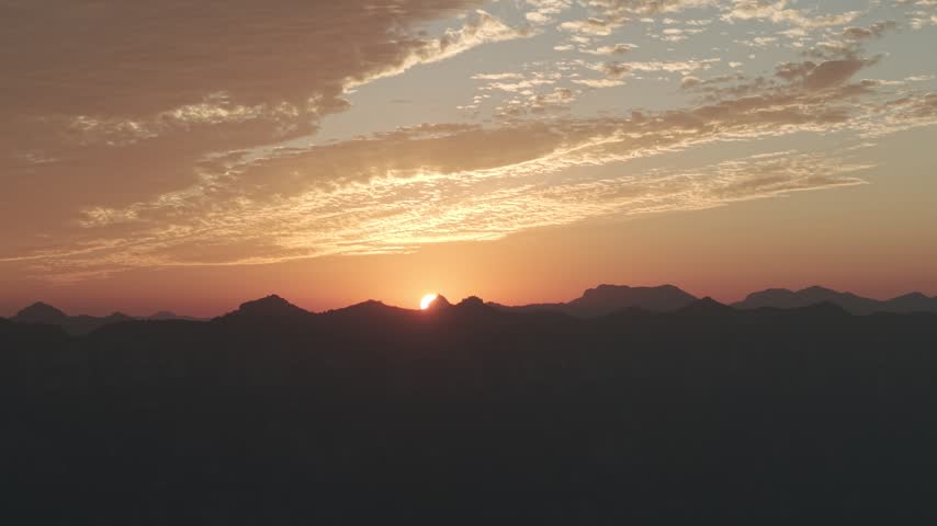Aerial view of a vibrant autumn sunset over Taihang Mountains, China. Pink and orange textured clouds fill the sky as the sun sets behind dark silhouettes of Wanxian peaks.