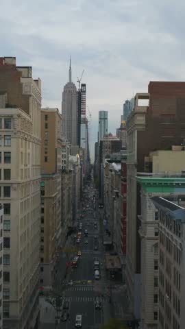Vertical video: Aerial views highlight a lively New York City street bustling with yellow taxi cabs, while the iconic Empire State Building towers in the background