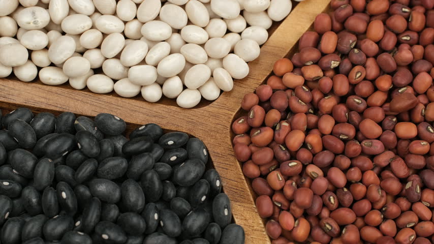 Different typed of beans. Dried white beans, red beans, black beans in wooden bowl, rotation