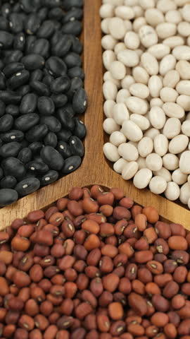 Mix Dried white beans, red beans, black beans in wooden bowl, rotation. Different typed of beans 