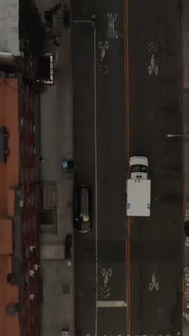Vertical video: Top down aerial overhead view of ambulance emergency services truck speeding through the streets and intersections in New York City