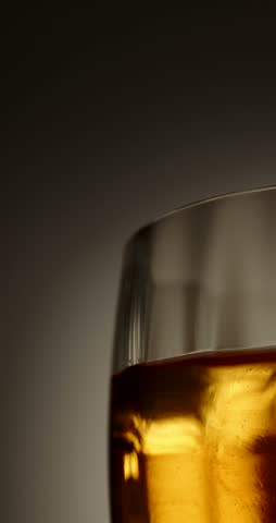 Close-up shot of golden whiskey or rum with ice in a luxury glass against a dark background, showcasing rich amber tones, elegant reflections, and premium drink lighting.