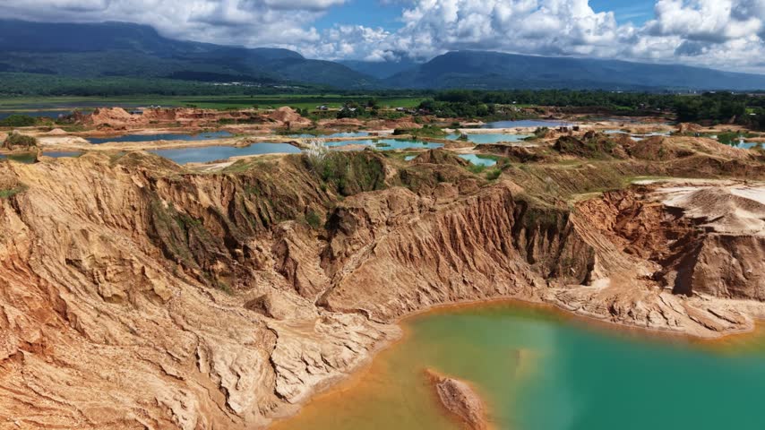 Eroded ridges and turquoise pools of a stone quarry below green hills, Sylhet, Bangladesh