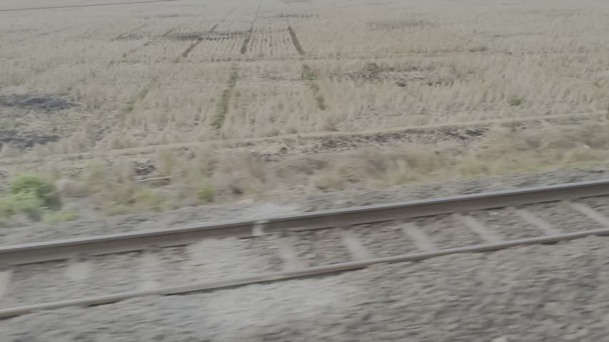 High speed motion blur view of railway tracks and gravel ballast from a moving train.