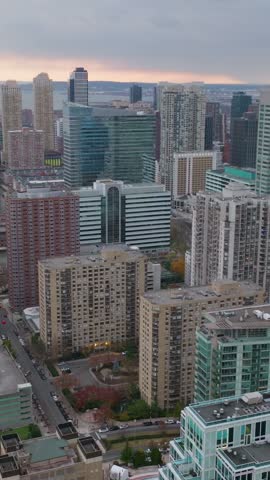 Vertical video: Aerial view of Jersey City skyline at sunset, showcasing modern buildings, urban landscape, and the waterfront area