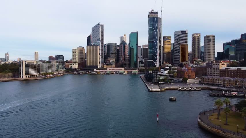 Amazing aerial establishing shot flying backwards from the sydney skyline across the water, revealing the iconic sydney harbour bridge