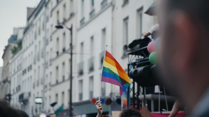 Activist waving a rainbow flag in a crowd during a pride march, celebrating equal rights