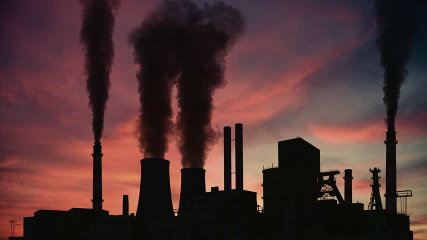 Factory chimneys smoking against a sunset sky. Air pollution, industrial emission and climate problem