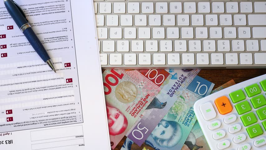 New Zealand taxes. Financial concept. Individual Tax Return filing. An IR3 paper form resting on a keyboard, alongside New Zealand dollars and a calculator. Flat lay, close-up, Business background 