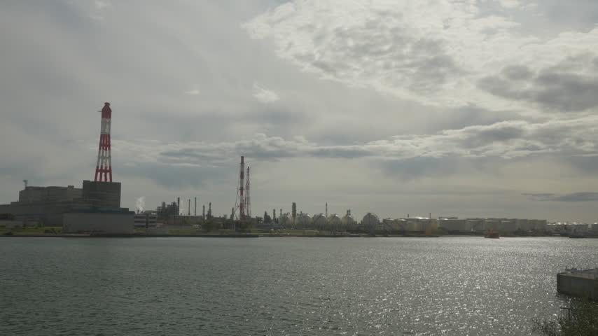 Distant view of industrial refinery zone and cargo shipping port across the water in Tomakomai, Hokkaido, Japan. Fixed 4K video.
