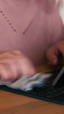 Woman hands cleaning her tablet screen with a cloth. Hygiene, technology. Closeup. Female person wipe a digital device with sanitizer for dirt, dust, germs. Cleaning laptop. Disinfecting of workspace