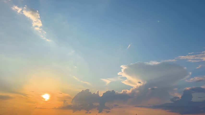 Bright sun setting over the horizon, changing the sky from blue to a warm, colorful orange