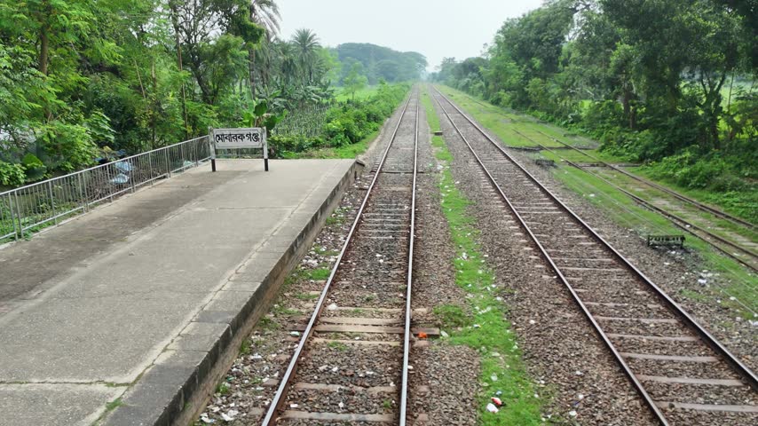 Straight Railway Tracks Leading through Rural Landscape next to Station Platform