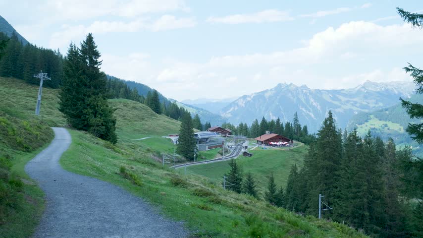 Beautiful mountain scenery with a winding trail leading to a small village in the swiss alps. Switzerland