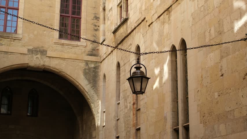 Authentic old lantern suspended from a long metal chain in the galleries of Saint-Just-et-Saint-Pasteur Cathedral in Narbonne, Aude, Occitanie, France. Minimal. View from below. Copy space.