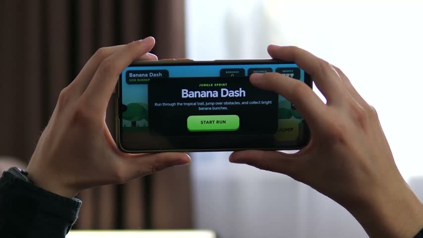 Person plays a colorful side-scrolling mobile game on a smartphone, jumping over obstacles and collecting rewards in a fast-paced casual gaming session.