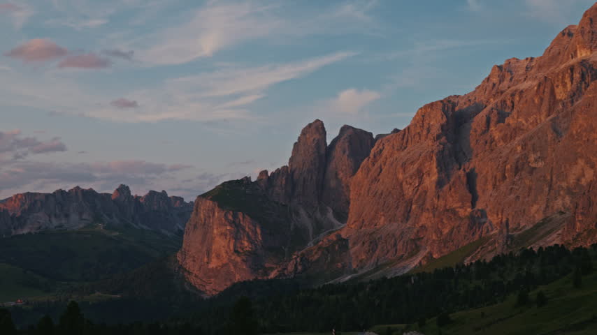 Panorama of scenic mountain landscape in South Tyrol, Italy, wide panning view of jagged peaks in golden hour light. Sunset wide scene of rugged limestone ridges and mountain slopes in Italian Alps